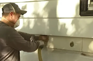 Worker installing side wall insulation