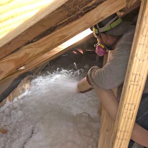 Worker installing blown in insulation