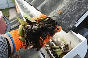 Hand cleaning debris out of gutters.