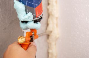 Worker using handheld tool to air seal a seam.